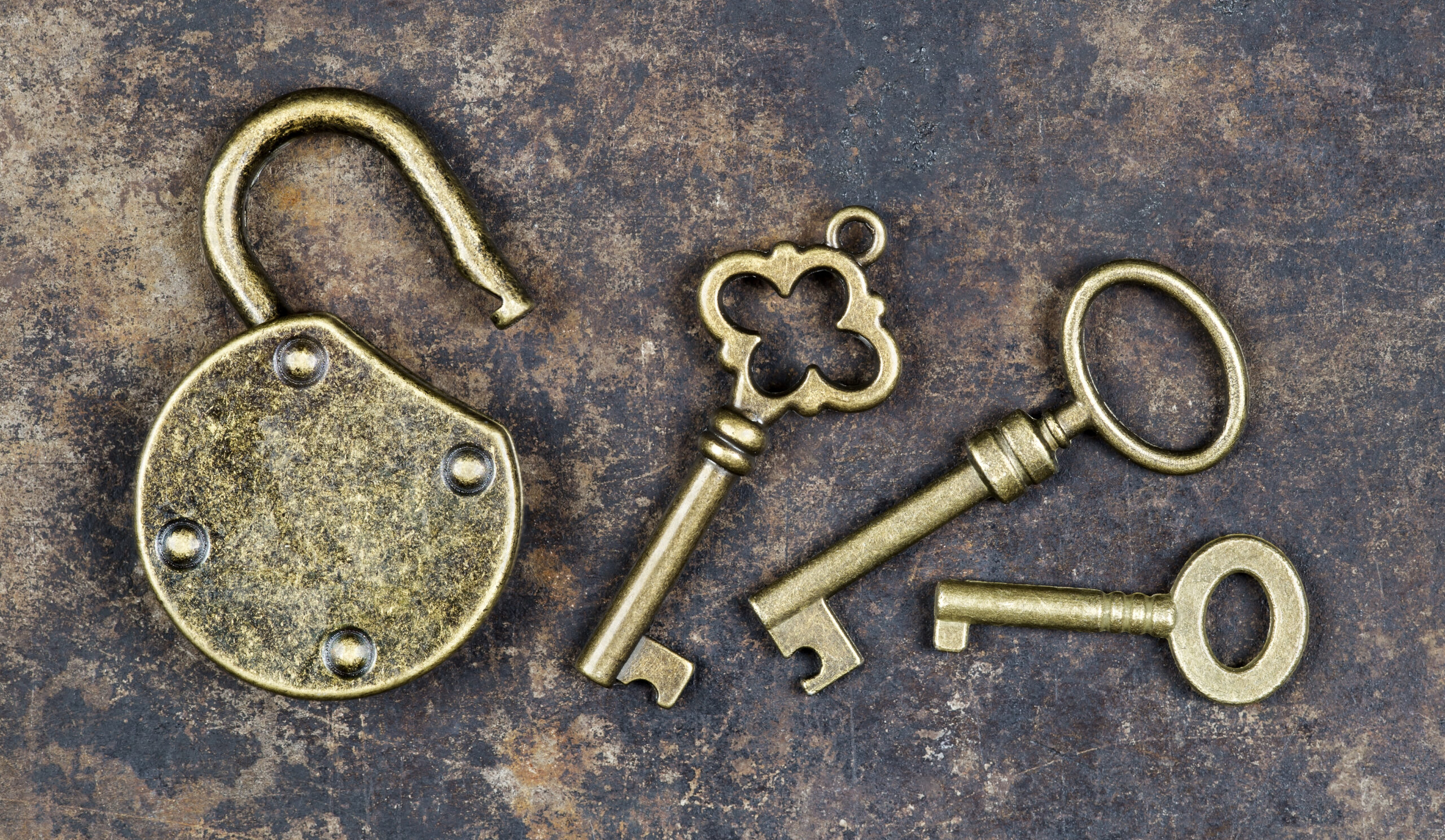 Antique keys and padlock on a rusty metal background
